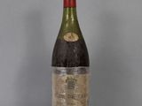 an old bottle of wine sitting on top of a glass table