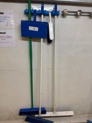 deux balais et une brosse posés par terre dans une pièce