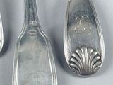 three silver spoons and two silver spoons sitting on a table