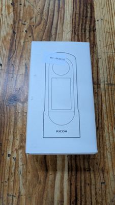 une photo représentant une boîte contenant un téléphone portable, posée sur une table en bois