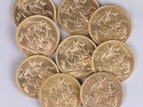 a close up of a pile of gold coins on a white surface