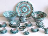 de nombreuses pièces de poterie bleues et vertes posées sur une table