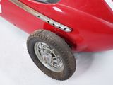 a small red toy car that is sitting on a white surface