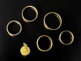 plusieurs bagues en or et une pièce d'or posées sur une surface noire