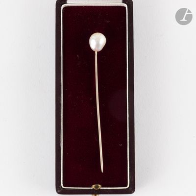 une image représentant une broche ornée d'une perle, dans une boîte