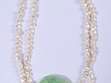 collier de perles avec une pierre verte et des perles sur fond blanc