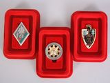 three red trays holding three different types of jewelry on top of a white surface