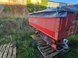 a red trailer with a tarp on it sitting in the grass