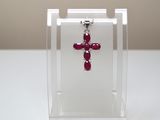 une petite croix rouge exposée dans une boîte transparente