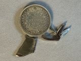 une médaille d'argent entourée d'un ruban, posée sur un morceau de tissu