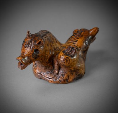 figurine représentant un cheval couché sur le dos sur une surface grise