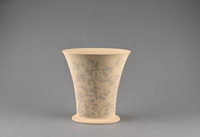 a white vase with a design on it on a gray surface
