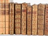 several old books are lined up on a shelf in a library