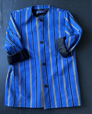 un manteau rayé bleu et jaune accroché à un mur noir