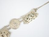 silver necklace with a coin and a coin on it on a white surface