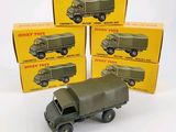 quatre camions militaires miniatures posés devant une pile de cartons