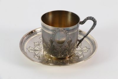 une tasse et une soucoupe anciennes en argent, posées sur un plateau en argent
