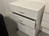 a white chest of drawers in the corner of a room