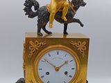 une horloge en or surmontée d'une statue représentant un homme à cheval