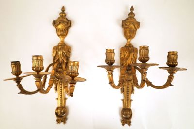 two gold colored candles on the wall next to each other