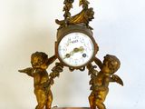 a small clock with angels on it on a marble base