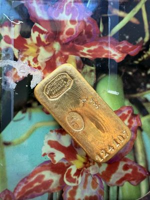 un lingot d'or posé sur une assiette, avec des fleurs en arrière-plan
