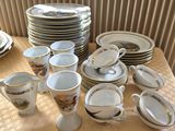 many cups and saucers on a table with a yellow tablecloth