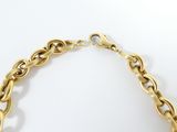 a close up of a gold chain bracelet on a white surface