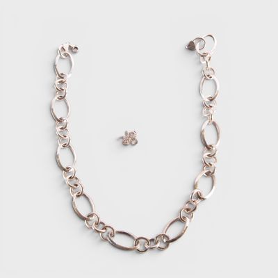 un gros plan d'un collier et d'une boucle d'oreille posés sur une surface blanche