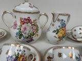four cups and saucers and a teapot on the table