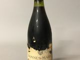 a bottle of red wine sitting on top of a white table