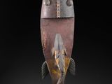 un gros plan sur une sculpture représentant un poisson, sur fond noir