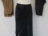 the black skirt is hanging on a clothes rack in front of a white wall
