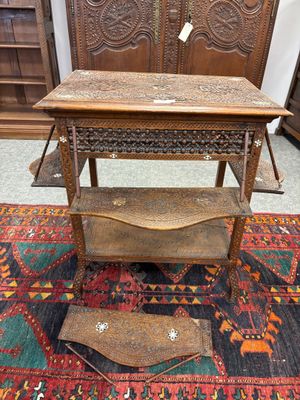 une vieille table en bois avec une étagère posée sur un tapis