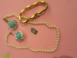 un collier, un bracelet et une bague posés sur un fond rose