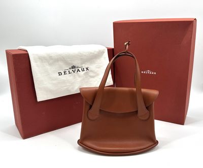 a brown handbag sitting next to a red box on a white surface