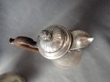 a silver teapot with a wooden handle on a table