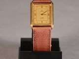 an image of a gold and pink watch on a black stand