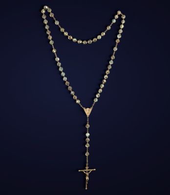 un chapelet orné d'une croix et d'une chaîne en or sur fond sombre
