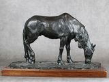 statue d'un cheval posée sur un socle en bois, sur fond gris