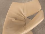 beige leather chair with curved seat and foot rest on concrete floor
