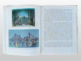 a book open to a picture of a city and a lake