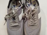 pair of gray sneakers with white laces on them on a white surface