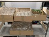 Des cartons contenant des verres à vin vides sont empilés sur un chariot dans une pièce
