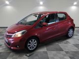 une Toyota Yaris rouge garée dans une pièce au sol en damier