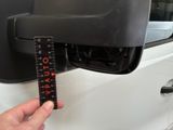 a person holding a ruler in front of a car door