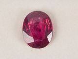 a close up of a red ruby stone on a white surface