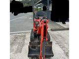 an image of a small red tractor parked in a parking lot