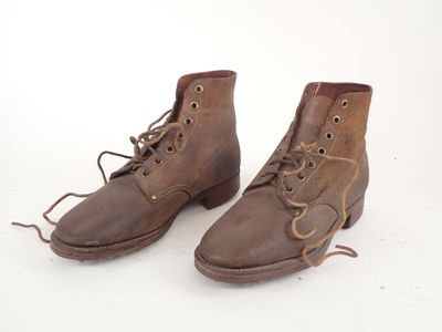 pair of brown leather boots with laces on them on a white surface