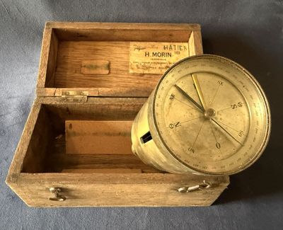 une vieille boussole en laiton dans un coffret en bois sur fond bleu